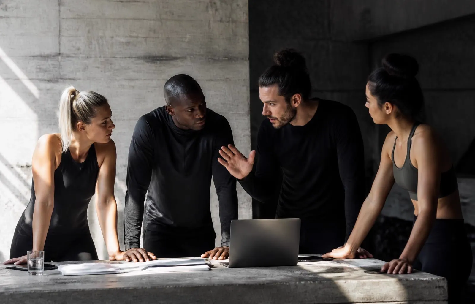 Four athlete founders in intense discussion around a concrete work table